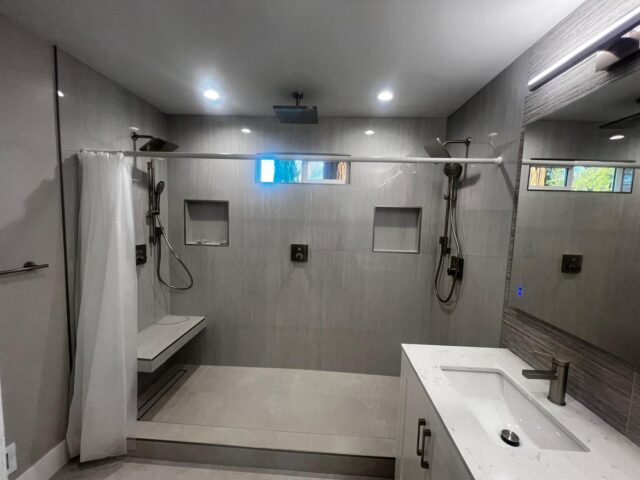 Newly remodelled shower and bathroom, with high quality, gray granite walls, and a newly installed sink.
